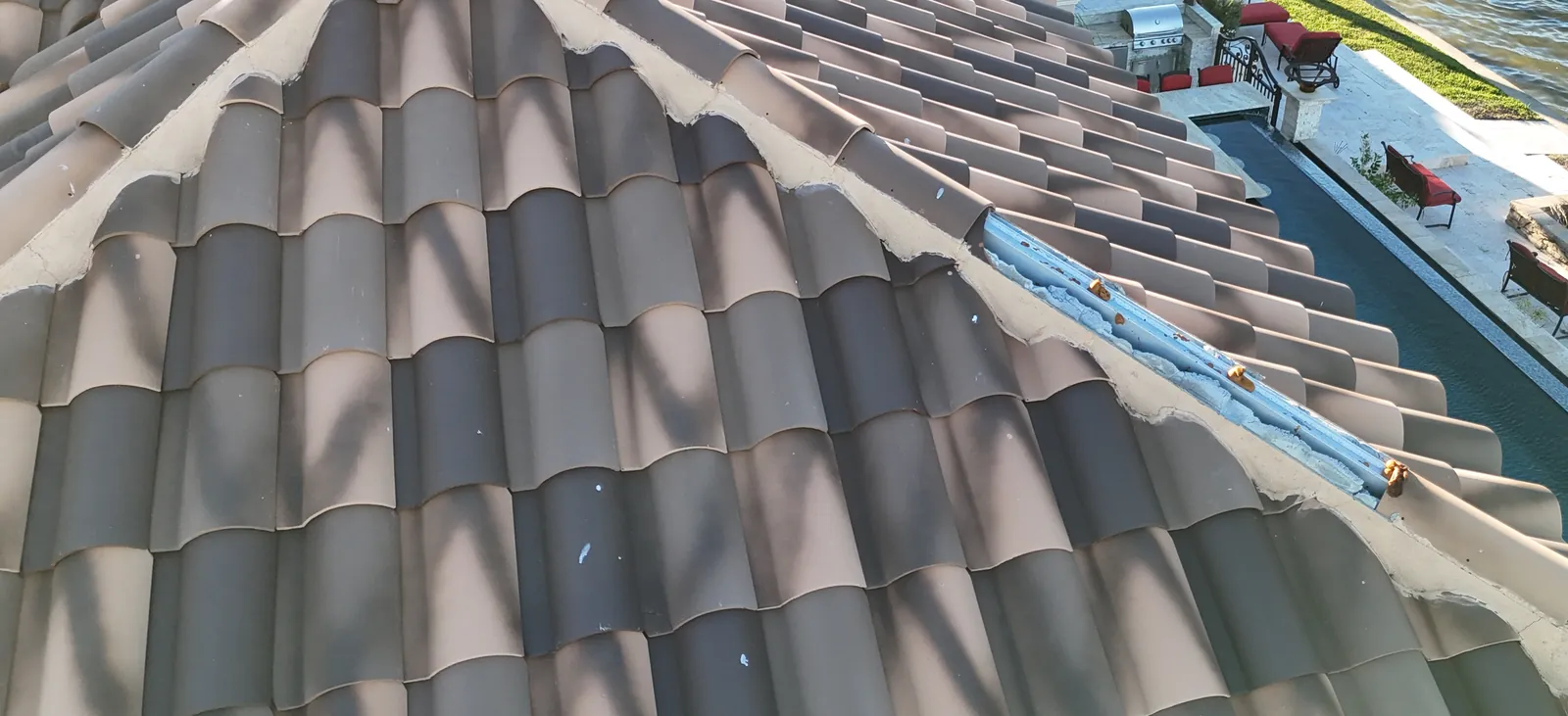 Roof hip with cap tiles missing, exposing the metal channel nailer that anchored them.