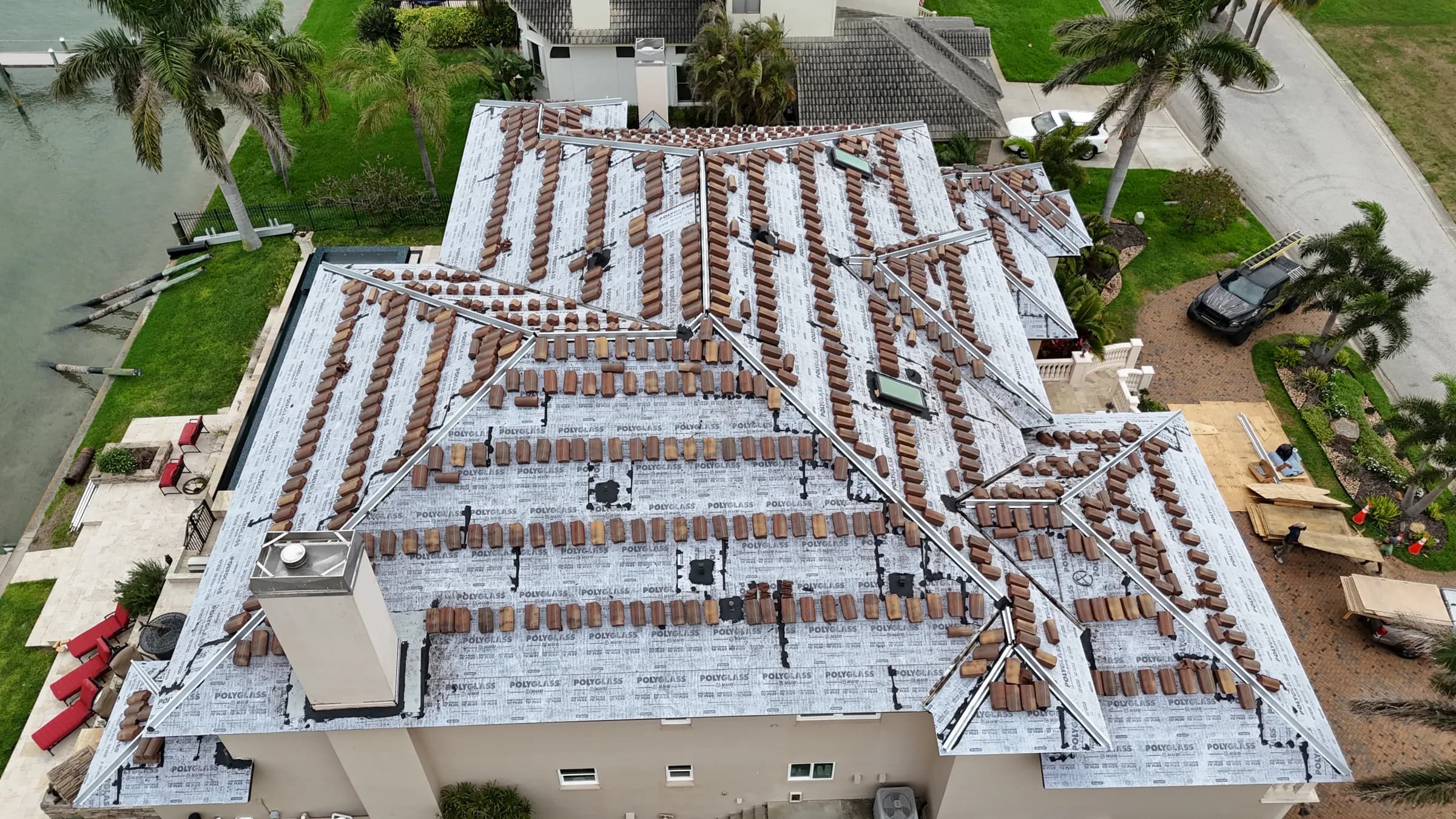 Straight-down aerial view of new clay tiles distributed in rows across the dried-in roof