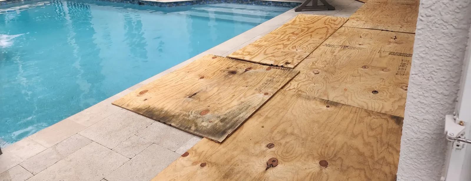 Plywood sheets laid over the paver pool deck beside the swimming pool to protect it during the roof work.