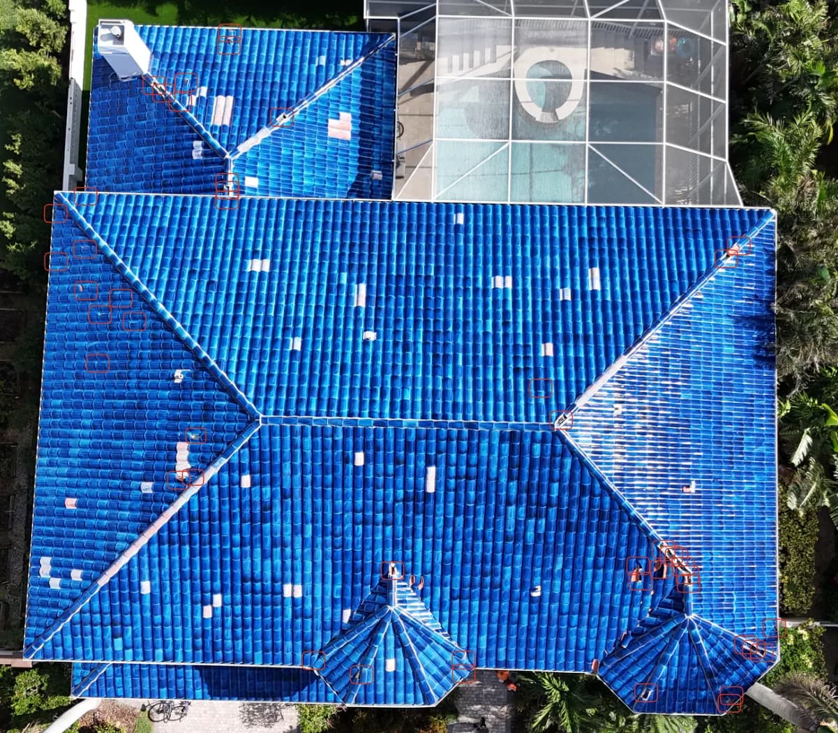 Straight-down drone photo of the blue tile roof with small red boxes marking damaged tiles across the slopes.