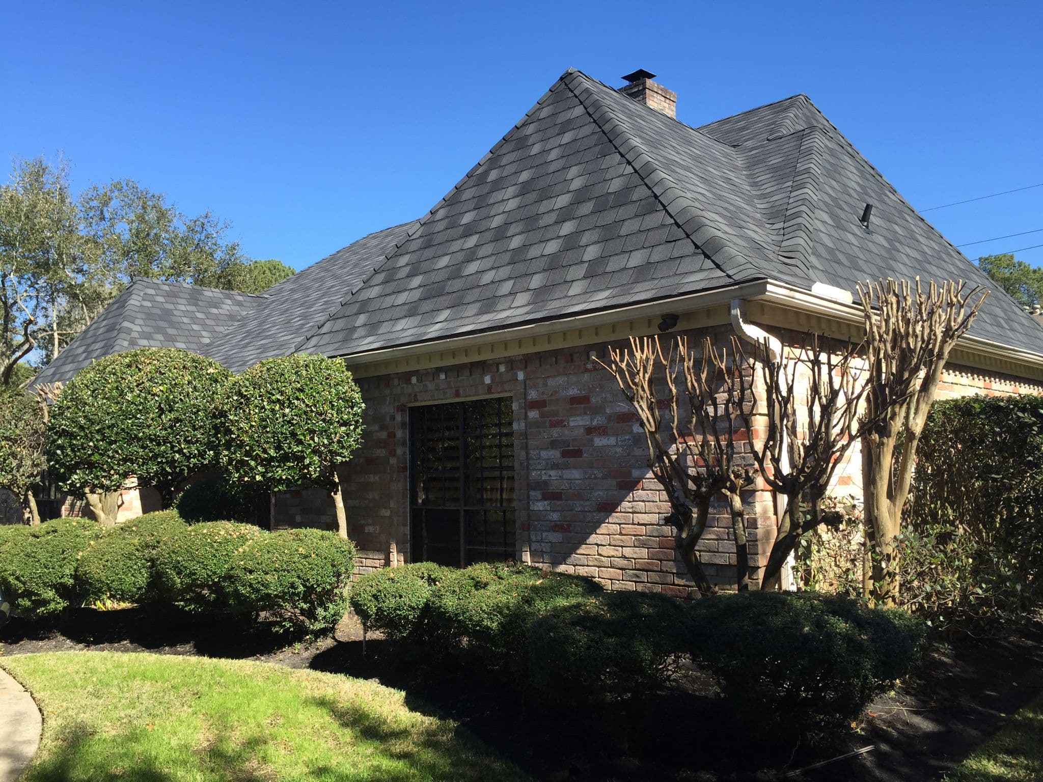Completed dark architectural-shingle roof on a brick home