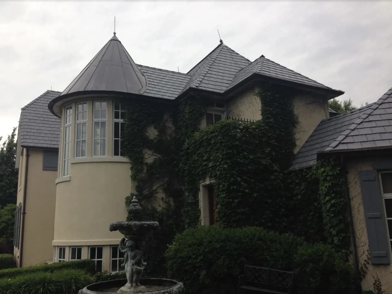 Large home with a dark natural slate roof and a metal-roofed turret