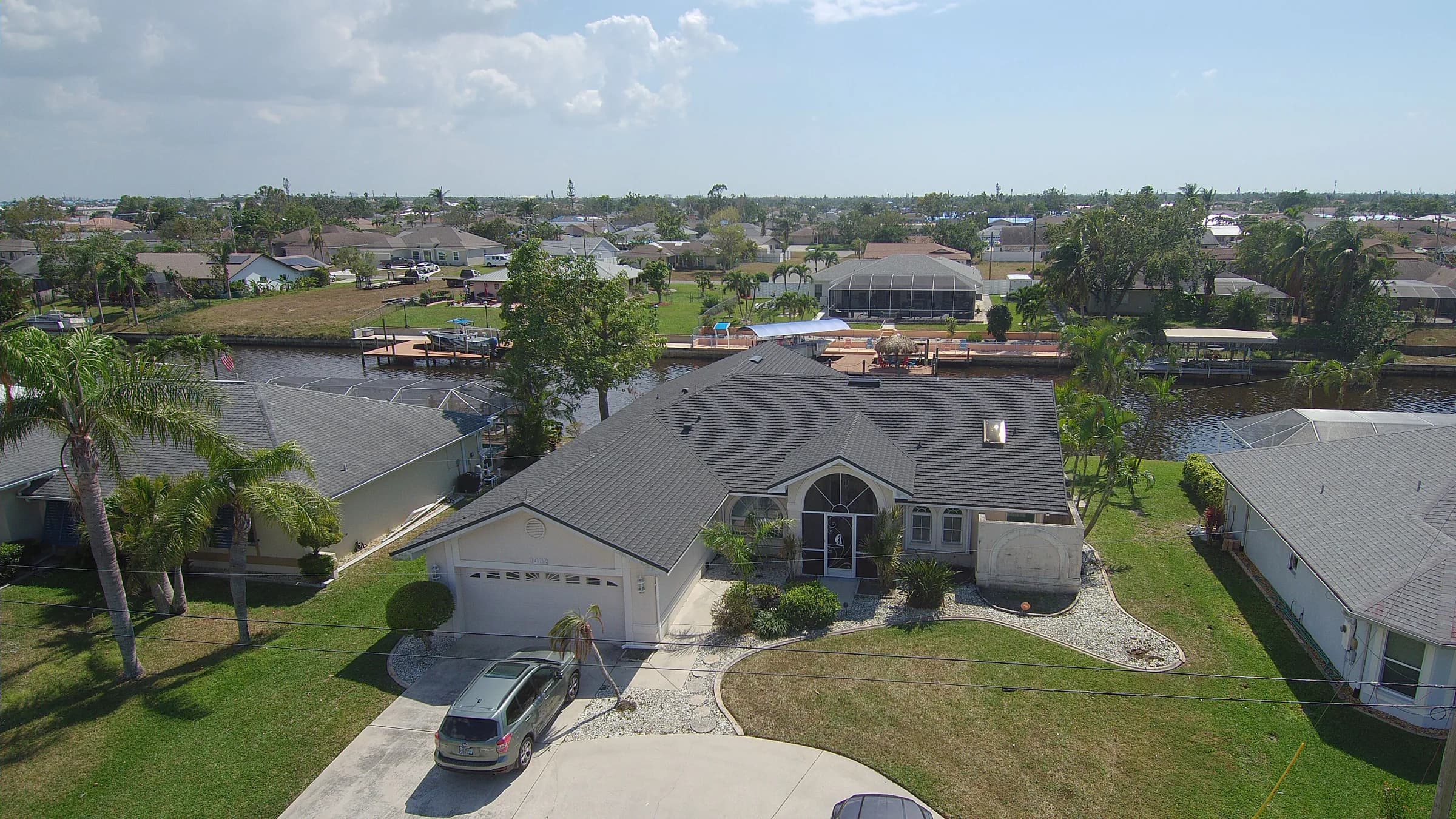 Aerial view of a finished dark gray stone-coated steel roof on a waterfront home