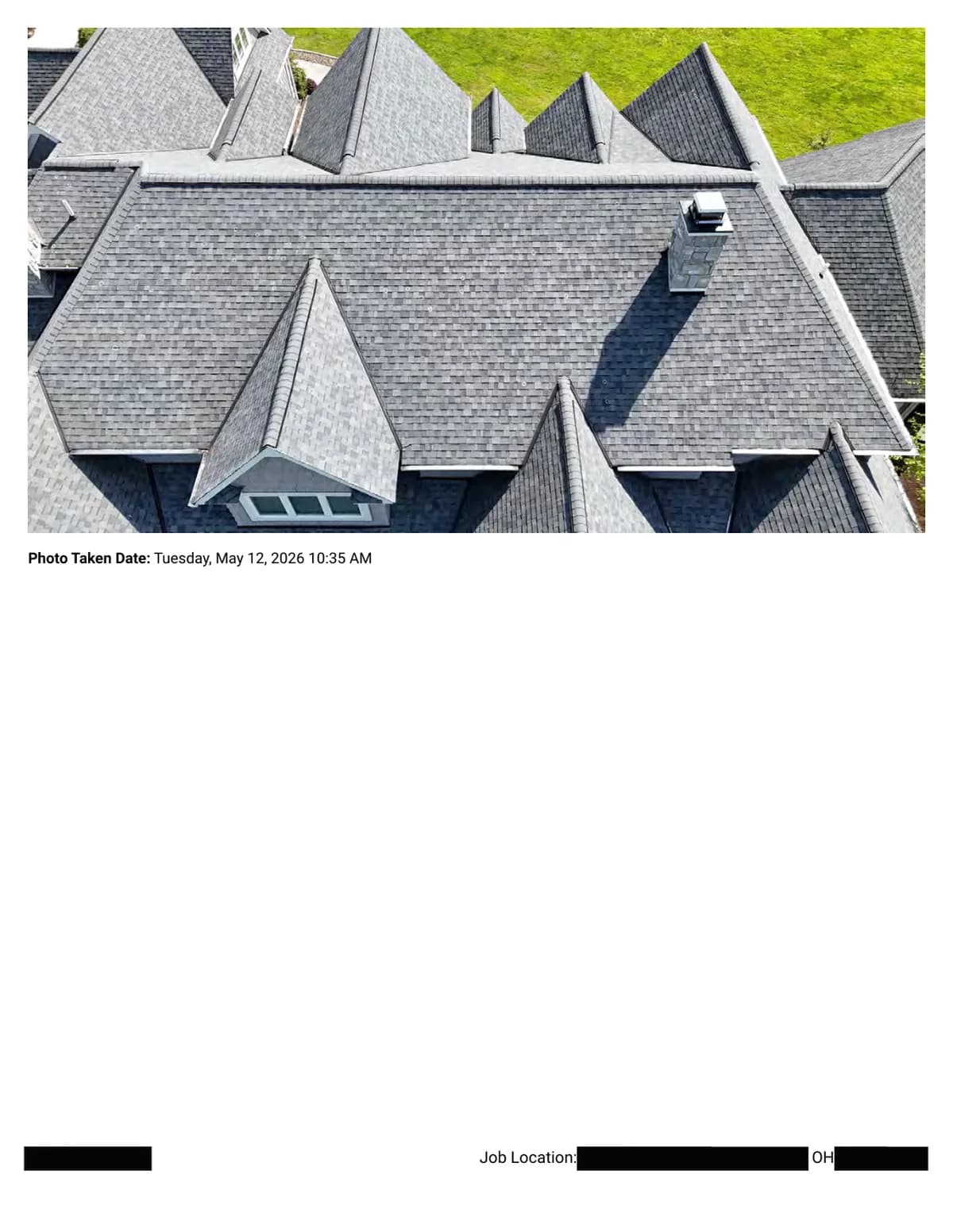 Wide aerial photo of the roof showing multiple slopes, hips, and a chimney, photographed for the damage assessment.