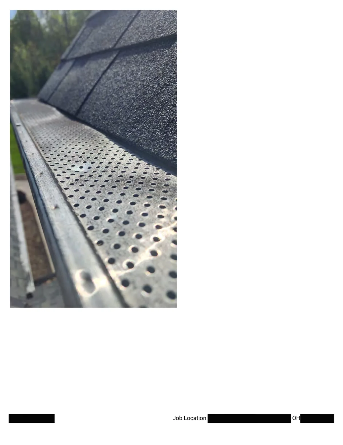 Another close-up of the perforated gutter guard showing a hail dent near the roof edge.
