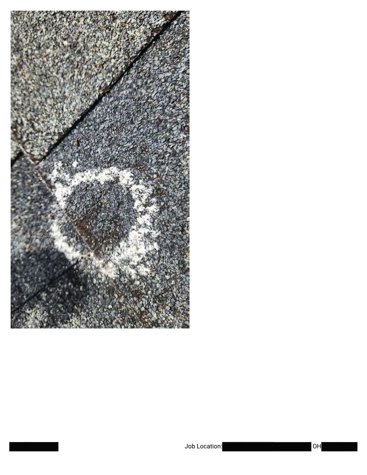 Extreme close-up of a chalk circle around a hail bruise at the corner of a shingle.