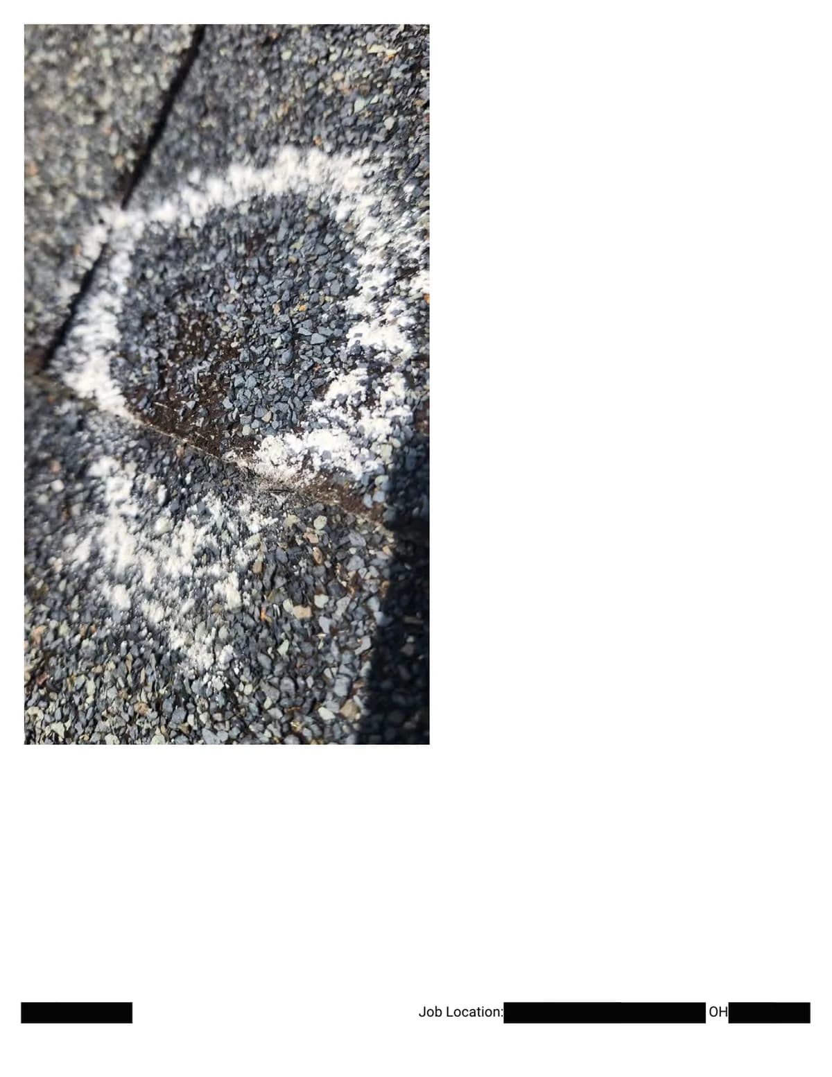 Extreme close-up of a chalk circle around an impact where granules are knocked away and the dark mat shows through.