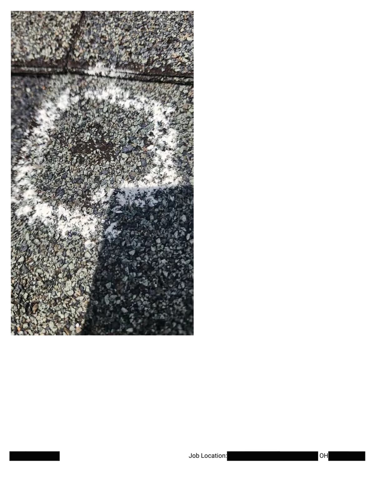 Extreme close-up of a chalk circle around a hail impact, photographed across a shingle shadow line.