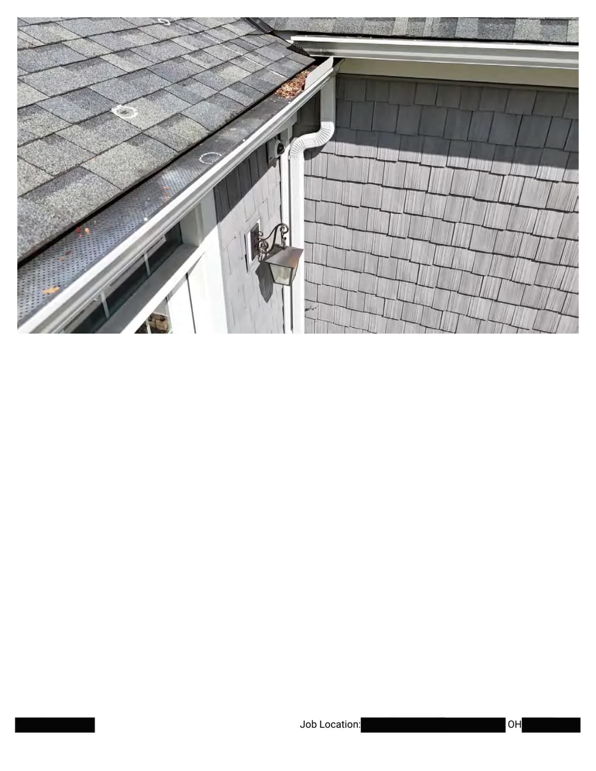 The roof edge at an eave corner: gutter, downspout, and wall shingles, with chalk circles marking impacts on the slope above.