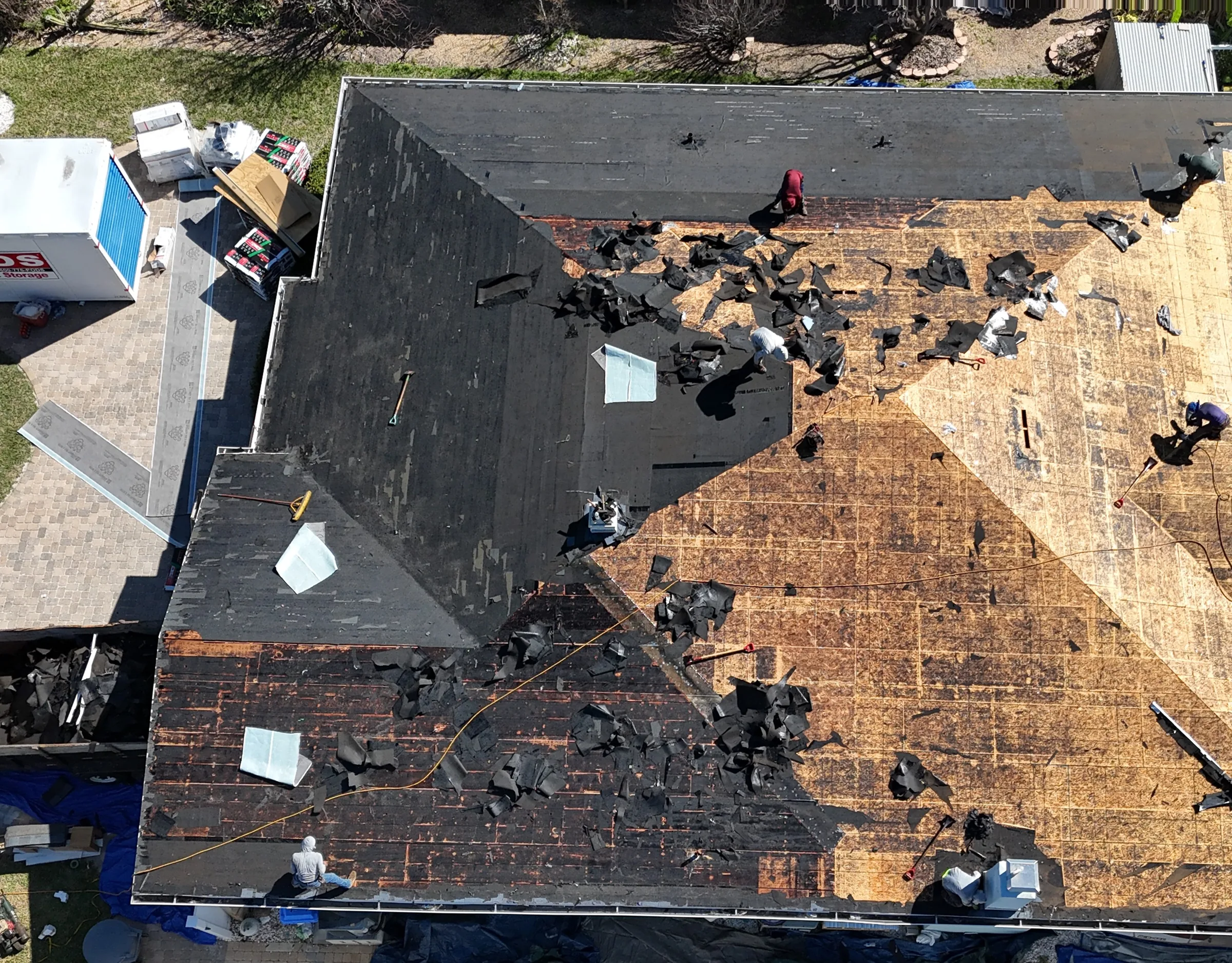 Overhead view of a residential roof during tear-off with the roof deck exposed