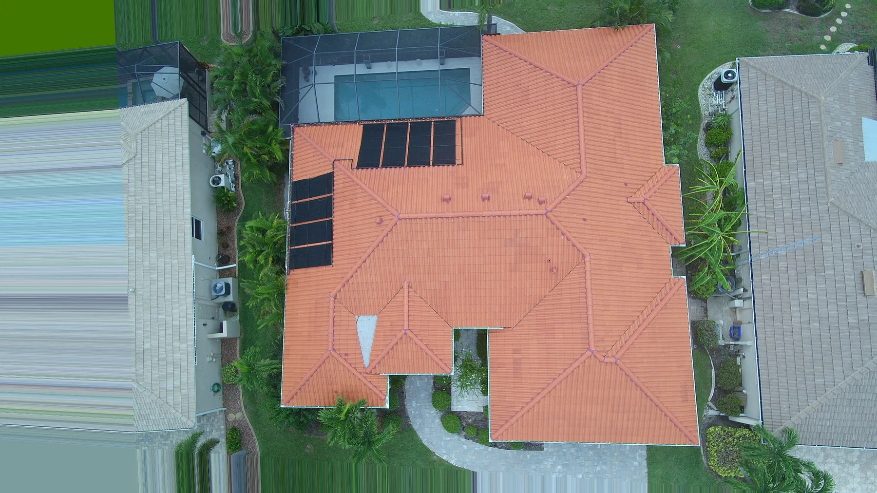 Overhead drone view of the same Cape Coral clay tile roof restored, with rebuilt ridge and hip lines and the solar array back in place